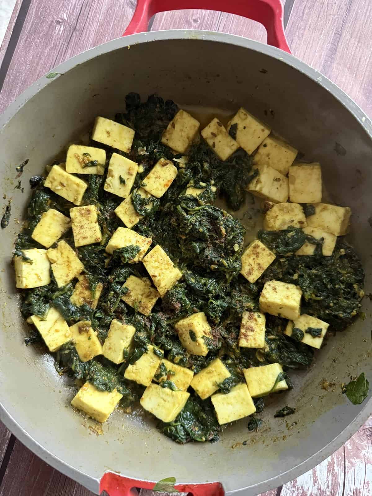 Paneer cubes folded into cooked spinach in a ceramic non-stick pan for easy 20-minute palak paneer.